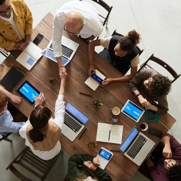 Top view of a diverse team collaborating in an office setting with laptops and tablets, promoting cooperation.